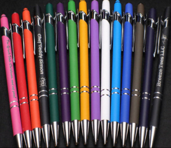 Assorted colored pens with metal accents on a black background