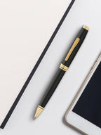 Black pen with gold accents on a white surface next to a tablet