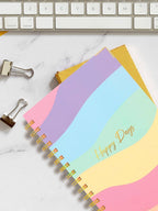 Set of colorful notebooks with 'Happy Days' on a marble surface with a keyboard.
