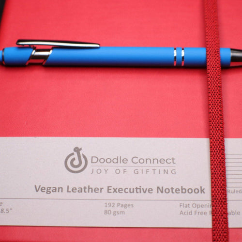 Red vegan leather executive notebook with a blue pen on a red background, featuring the Doodle Connect brand.