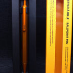 Orange pen in a black and yellow box on a dark background