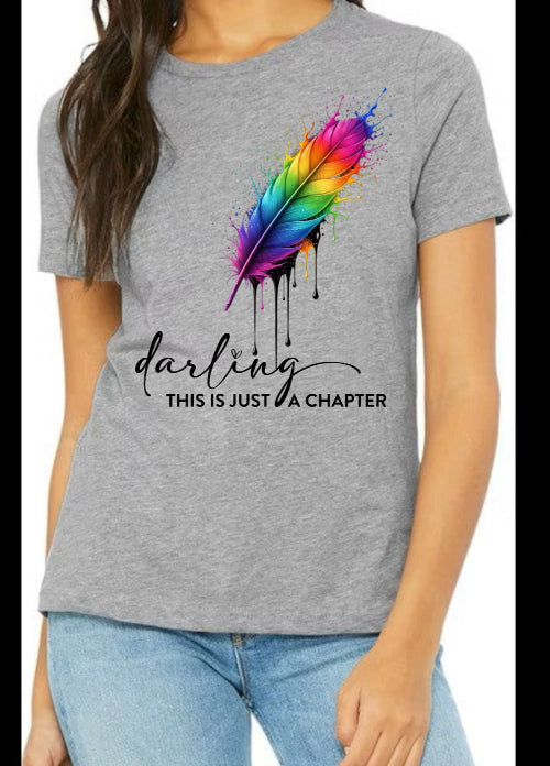 Gray t-shirt with colorful feather design and text worn by a person