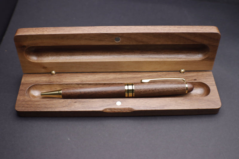 Wooden pen with gold accents in an open wooden case on a dark background